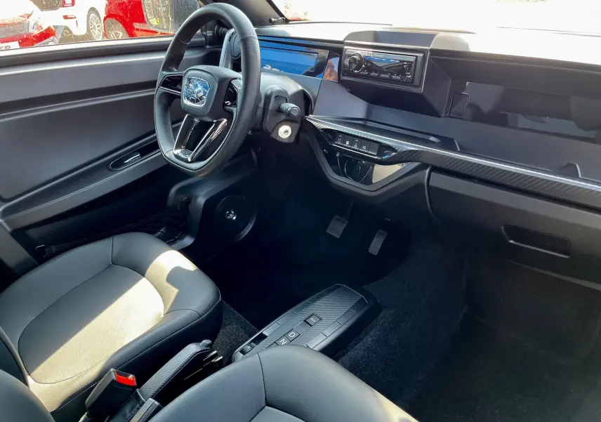 Intérieur noir du LIGIER Myli I.DEL 8KWH 2024 vu côté conducteur, avec tableau de bord moderne et boîte auto compacte.