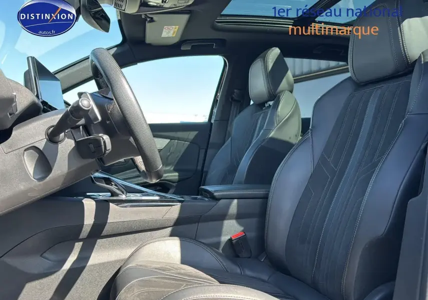 Intérieur du Peugeot 3008 2022, vue côté conducteur, sièges cuir noirs avec surpiqûres blanches et toit ouvrant panoramique.