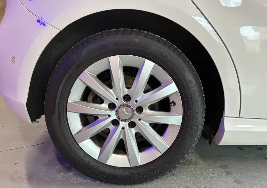 Gros plan sur la roue avant gauche blanche d'une Mercedes Classe A 200D 2016 avec jante alliage argentée.