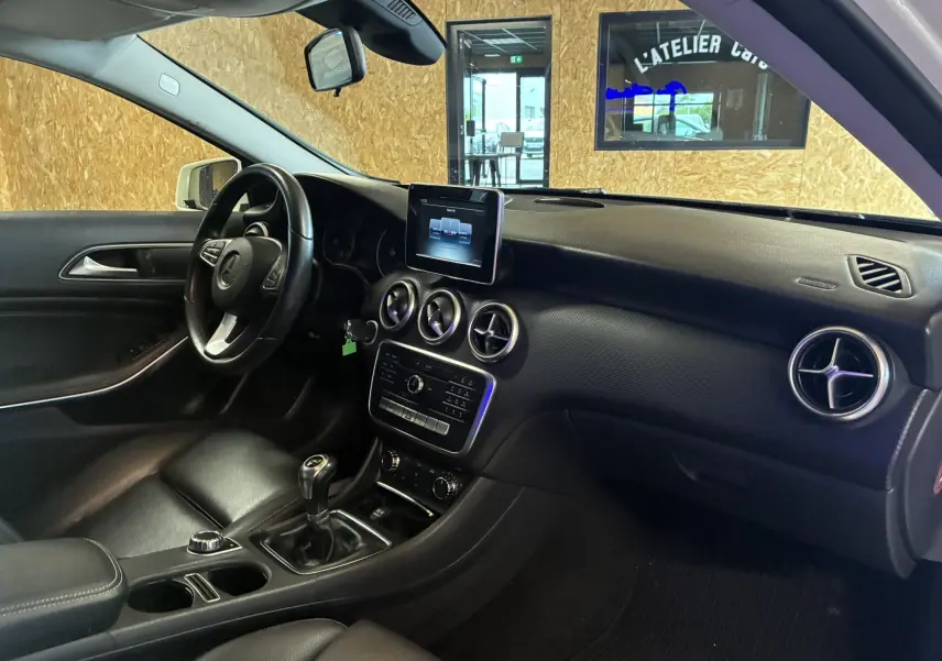 Intérieur noir de la Mercedes Classe A 200D 2016 vu côté conducteur, avec tableau de bord moderne et boîte manuelle.