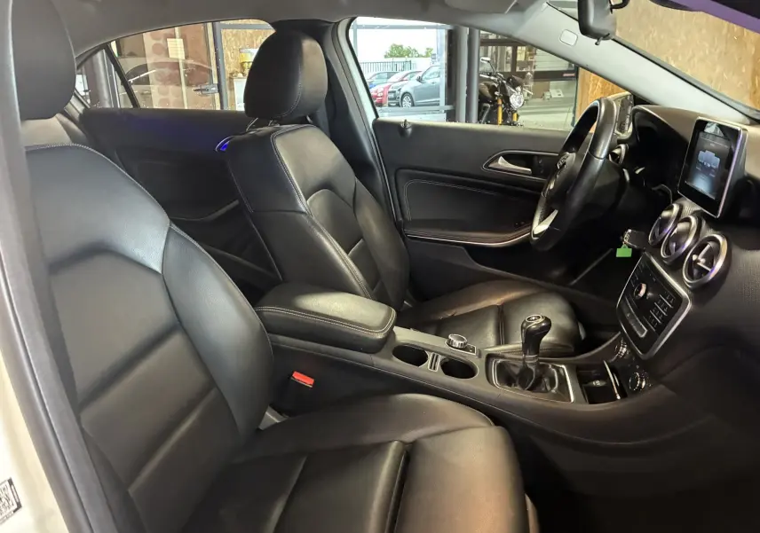 Intérieur noir cuir de la Mercedes Classe A 200D 2016, vue côté conducteur avec tableau de bord et boîte manuelle visible.