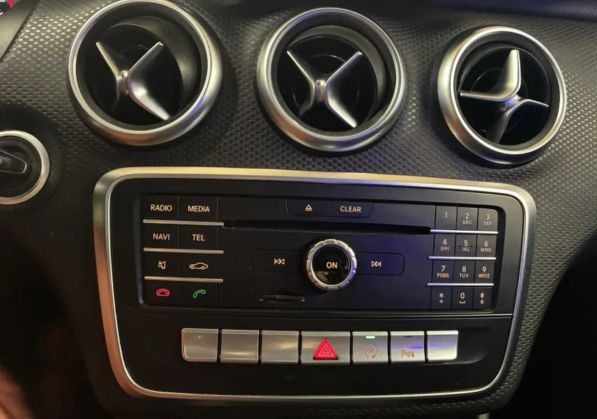 Vue rapprochée du tableau de bord noir de la Mercedes Classe A 200D 2016, avec commandes multimédia et aérateurs ronds chromés.