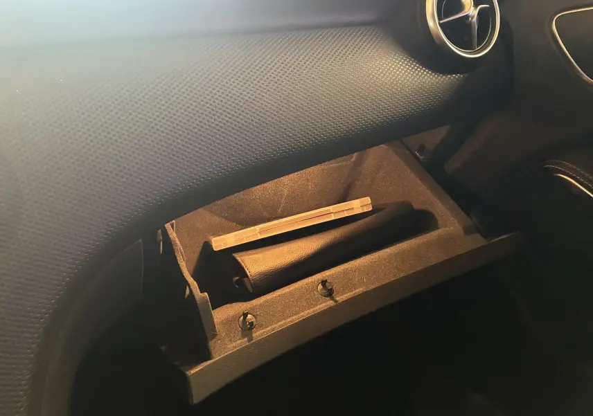 Gros plan sur la boîte à gants ouverte du Mercedes Classe A 200D 2016, intérieur noir avec détails en cuir et aérateur rond.