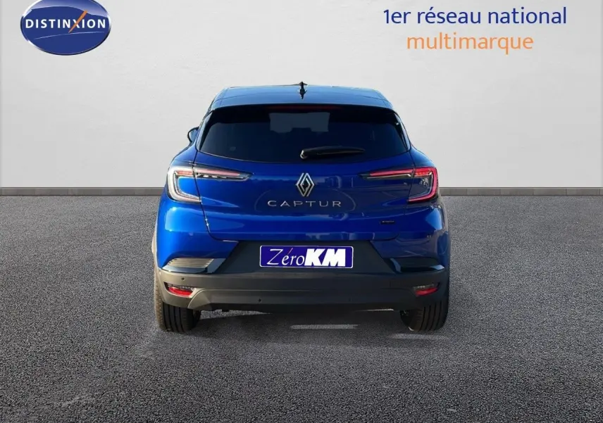 Vue arrière d'un Renault Captur E-Tech hybride bleu Iron Metal avec toit noir, en stationnement sur sol gris.