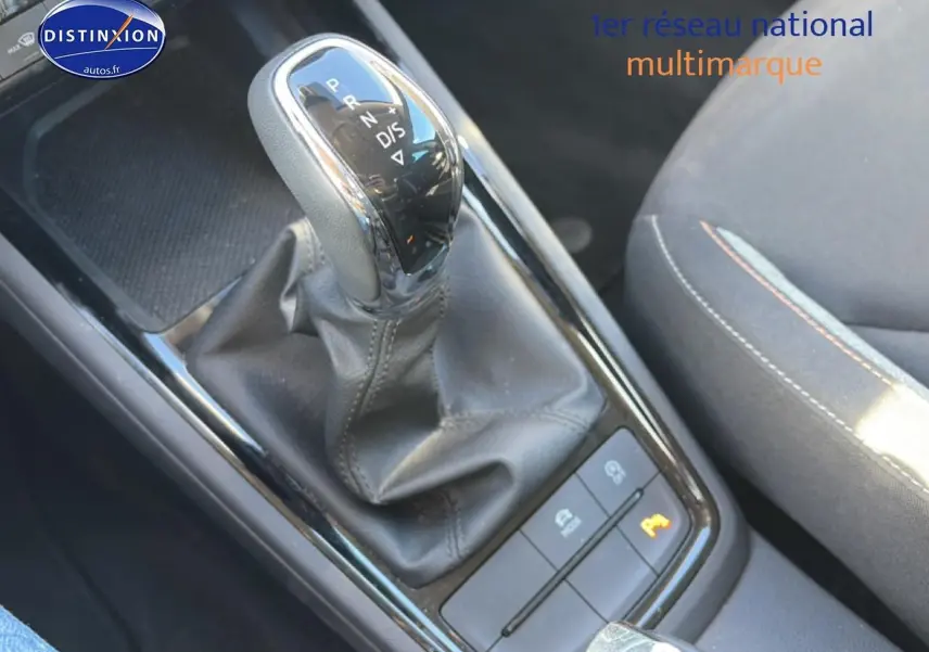 Gros plan sur le levier de vitesses automatique noir et chrome du Skoda Kamiq 2025, avec console et siège tissu visible.
