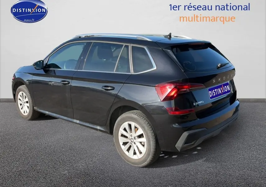 Vue 3/4 arrière droite d'un Skoda Kamiq noir 2025 avec jantes alu et barres de toit visibles.