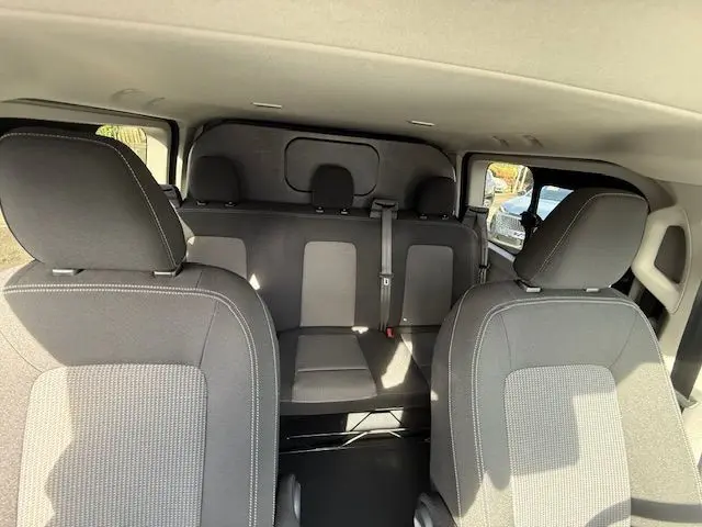 Vue intérieure arrière montrant les sièges en tissu gris du Volkswagen Transporter T7 ProCab L1H1 Business 2026.