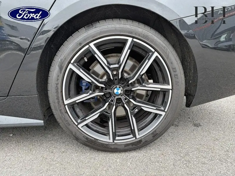 Gros plan sur la jante avant droite noire et argentée d’une BMW Série 4 Gran Coupe F36 Saphirschwarz métallisé.