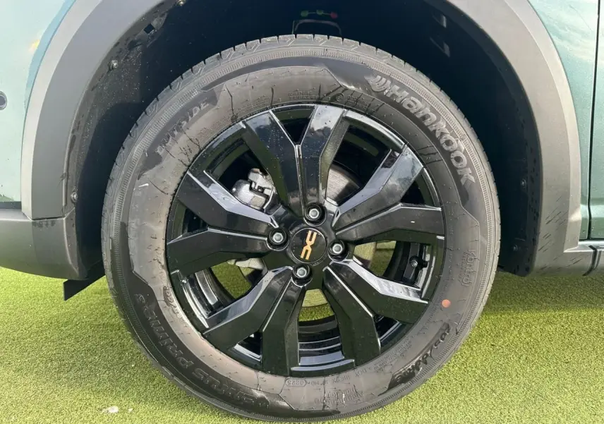 Gros plan sur la roue arrière droite noire brillante de la Dacia Sandero III Stepway Vert Cèdre avec jante aluminium 16 pouces.