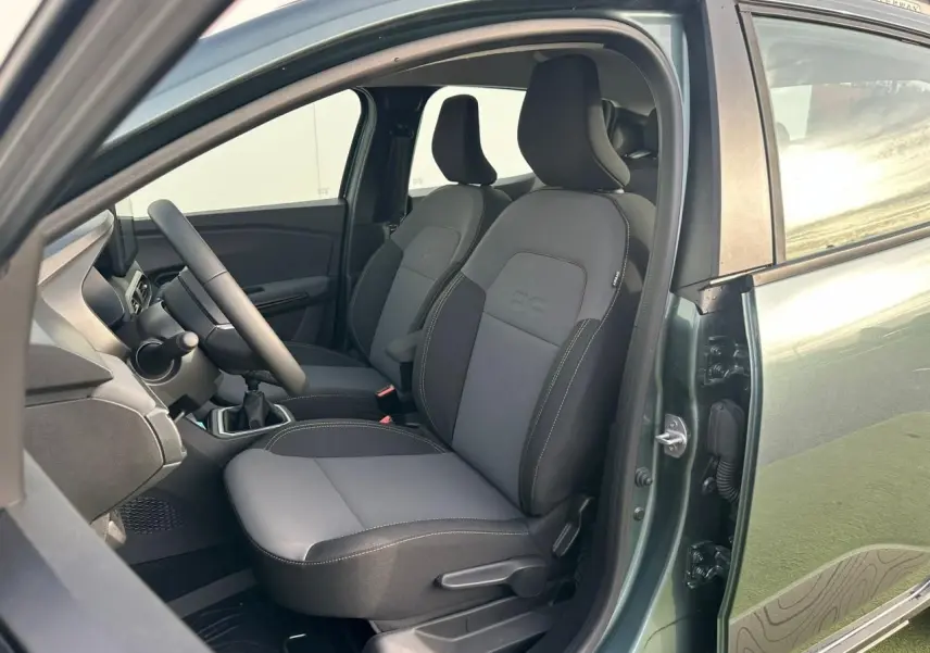 Vue intérieure côté conducteur de la Dacia Sandero III Stepway vert cèdre, montrant les sièges avant et le volant.