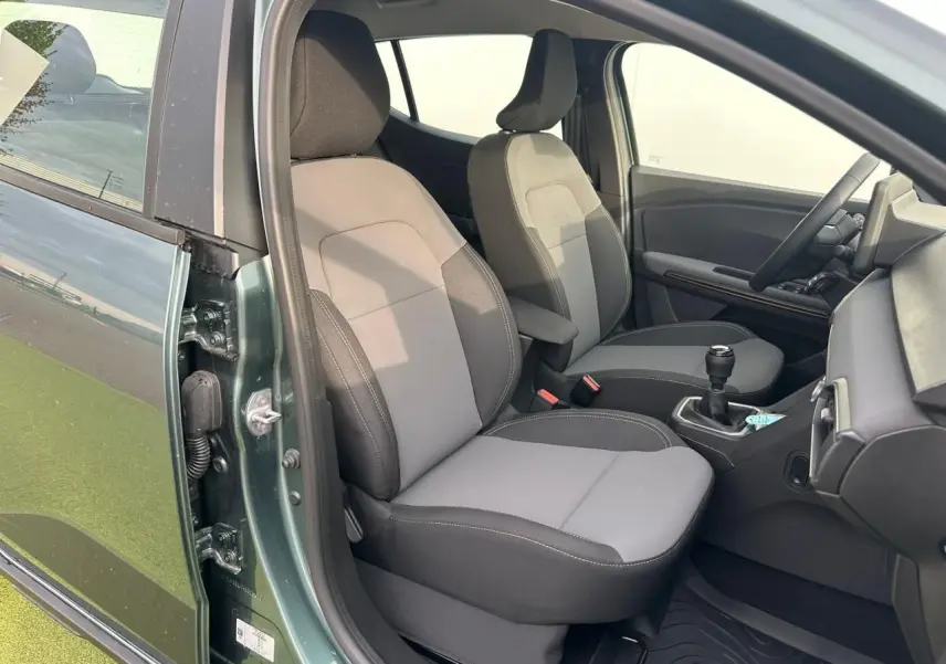 Vue intérieure côté conducteur de la Dacia Sandero III Stepway vert cèdre, montrant sièges et levier de vitesse manuel.