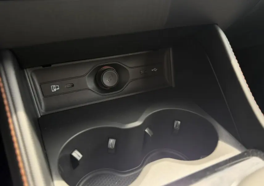 Gros plan sur l'accoudoir central avant noir du MG Motor EHS 1.5 Hybrid+ 224 Luxury avec porte-gobelets et prises USB.