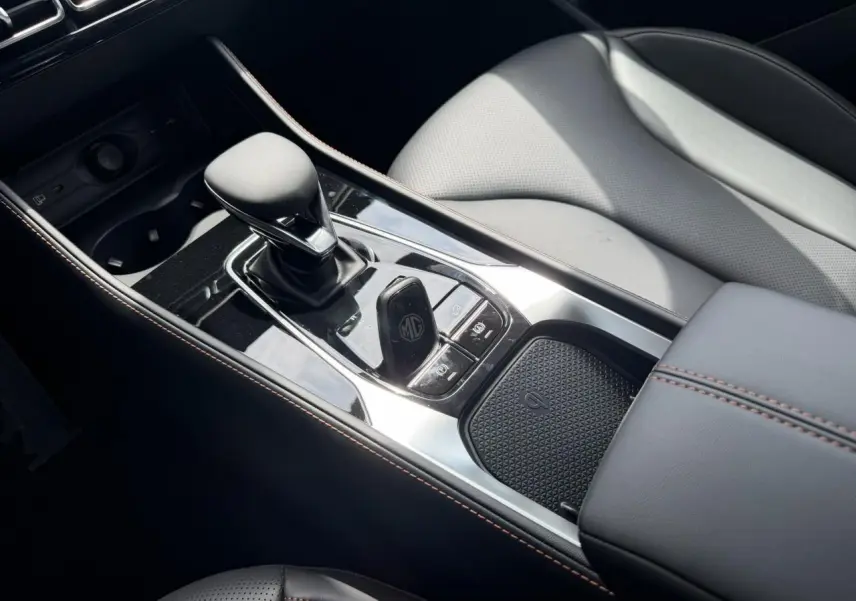 Vue rapprochée de la console centrale noire du MG Motor EHS 1.5 Hybrid+ 224 Luxury avec levier de vitesses et accoudoir.