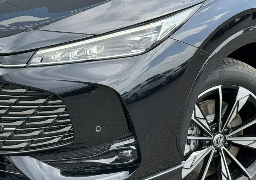 Gros plan sur l'avant droit noir métallisé du MG EHS 1.5 Hybrid+ 224 Luxury avec phares LED et jante alliage 19 pouces.