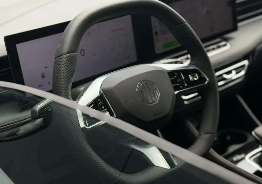 Vue rapprochée du volant noir perforé MG EHS 1.5 Hybrid+ 224 Luxury avec tableau de bord numérique et écran tactile.