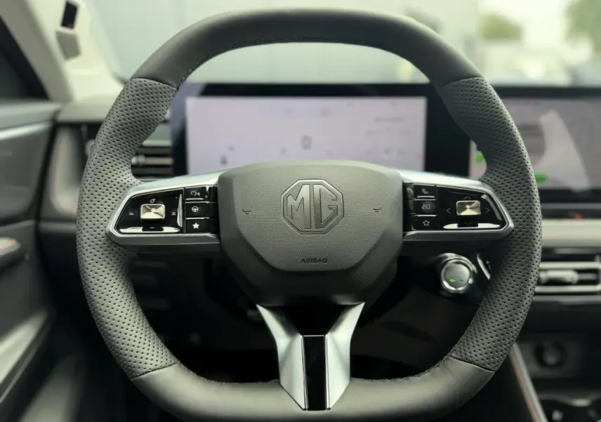 Vue rapprochée du volant noir perforé de la MG MOTOR EHS 1.5 Hybrid+ 224 Luxury avec logo MG central et commandes intégrées.