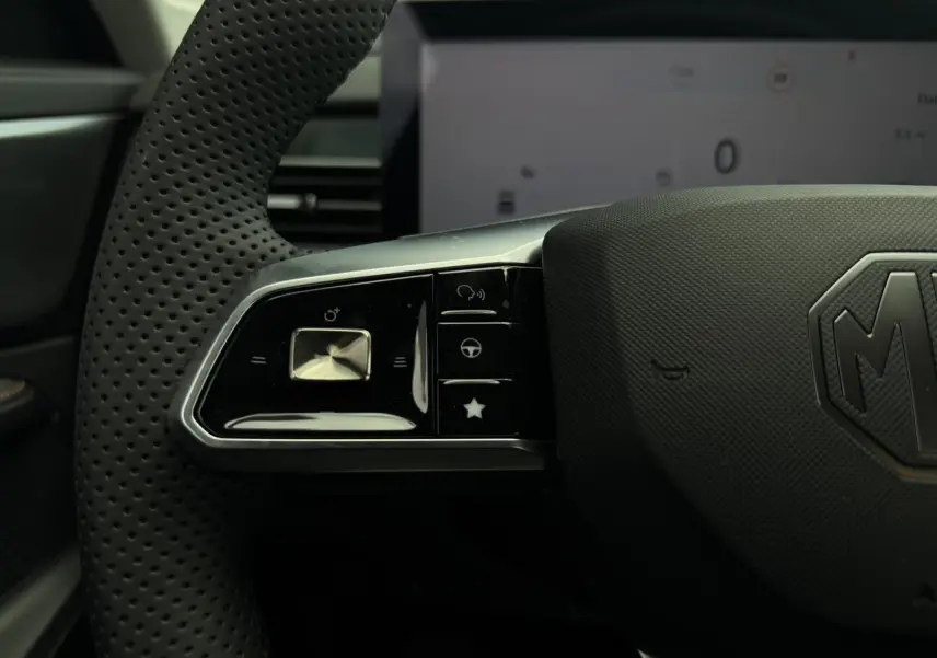 Gros plan sur la partie gauche du volant noir perforé du MG MOTOR EHS 1.5 Hybrid+ 224 Luxury avec commandes intégrées.