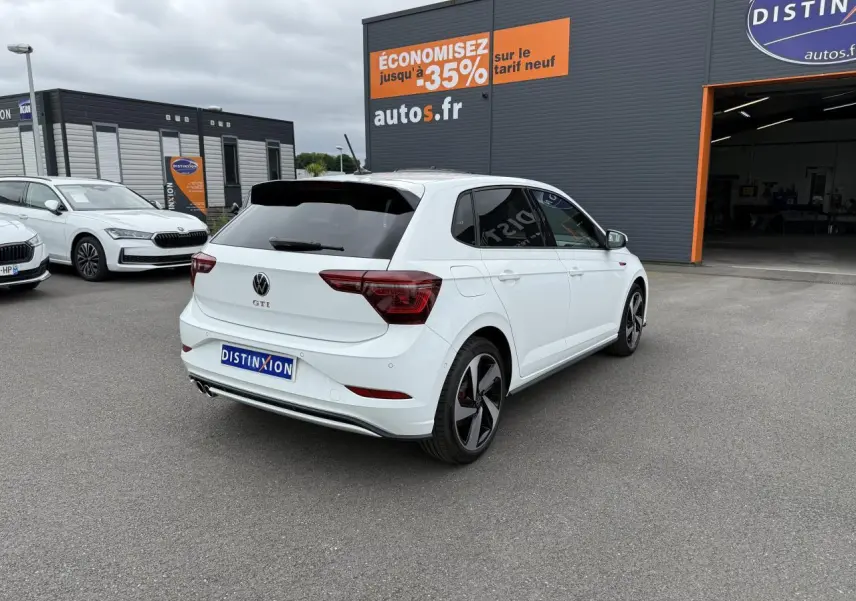 Volkswagen Polo GTI blanche vue 3/4 arrière droit, avec jantes sport et vitres arrière surteintées.