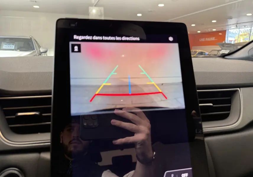 Écran tactile central montrant l'image de la caméra de recul du Renault Captur gris cassiopée dans un intérieur moderne.