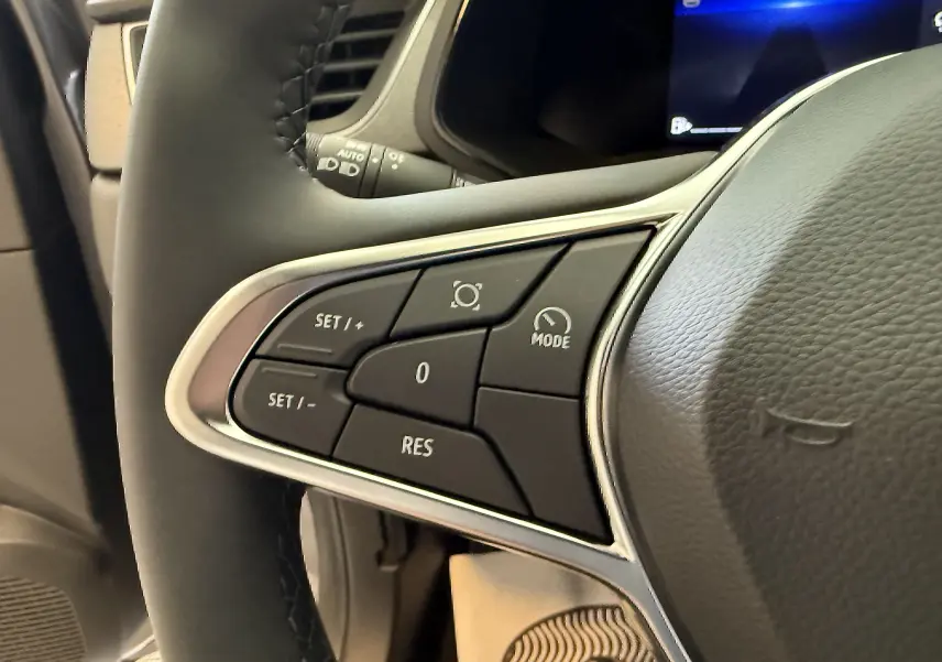 Gros plan sur les commandes de régulateur de vitesse au volant cuir noir du Renault Captur gris Cassiopée métal 2025.