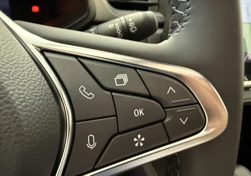 Gros plan sur les commandes multifonctions noires avec contour argenté du volant du Renault Captur gris Cassiopée 2025.