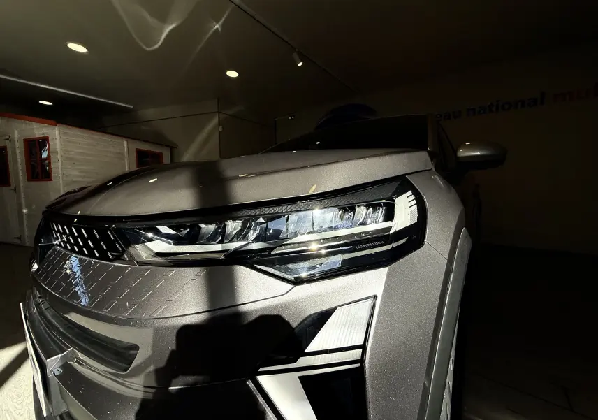 Gros plan sur l'avant droit du Renault Captur gris Cassiopée métal, mettant en valeur son phare LED et sa calandre texturée.