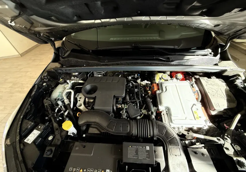 Vue plongeante sur le moteur hybride du Renault Captur gris Cassiopée, capot ouvert montrant les composants techniques.