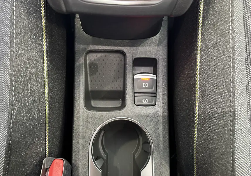 Vue en plongée sur la console centrale noire du Renault Captur gris, avec porte-gobelet et commandes électroniques visibles.