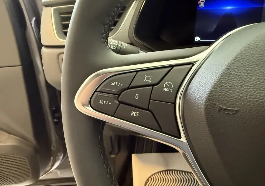 Gros plan sur les commandes de régulateur de vitesse au volant du Renault Captur gris Cassiopée 2025.