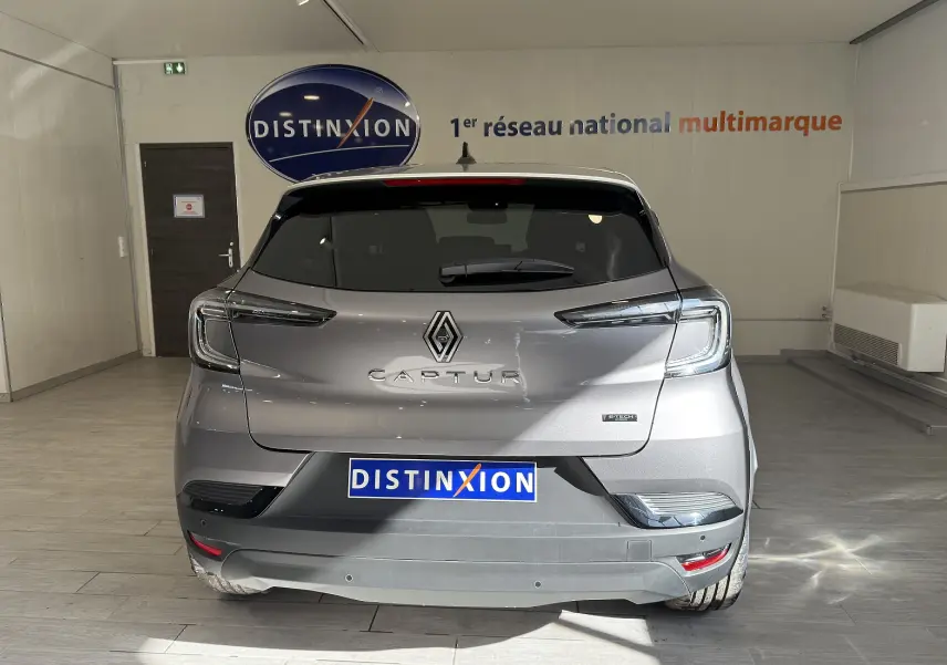 Vue arrière d'un Renault Captur gris Cassiopée métal avec toit gris, en showroom Distinxion, modèle hybride 2025.