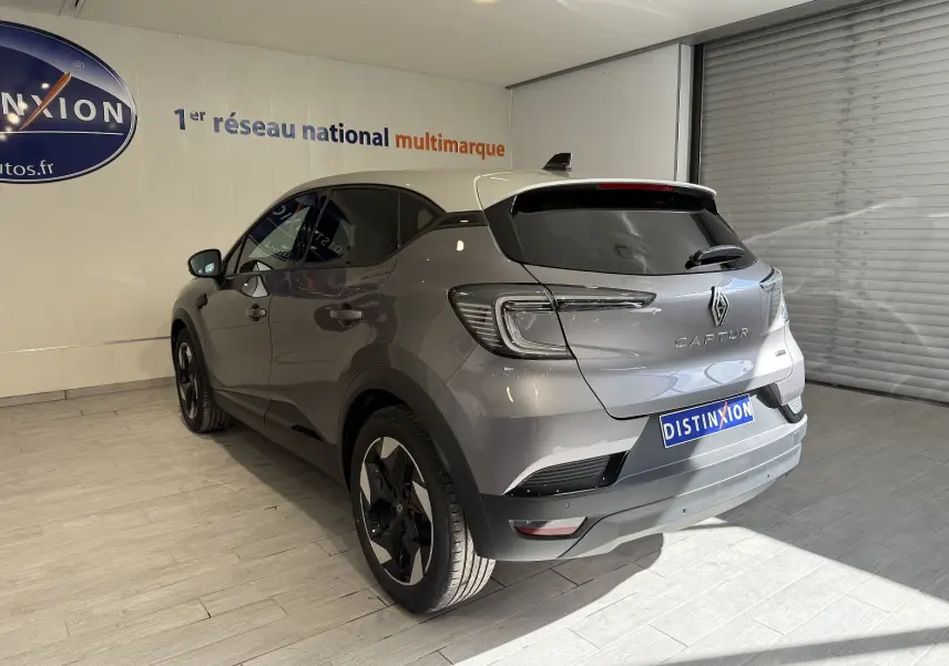 Vue 3/4 arrière droite du Renault Captur gris Cassiopée métal avec toit gris, en intérieur showroom lumineux.