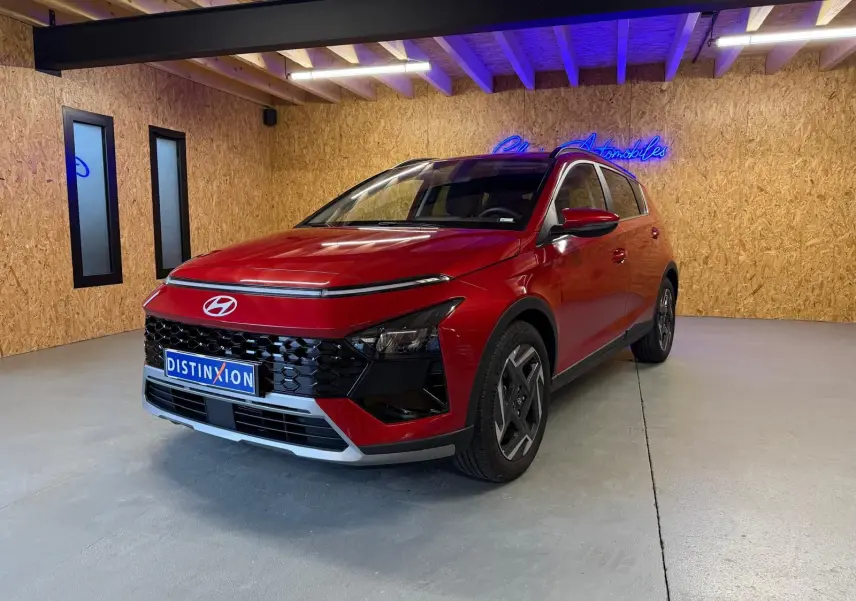 Vue 3/4 avant d'une Hyundai Bayon rouge avec calandre noir laqué et jantes alu 17 pouces dans un showroom.