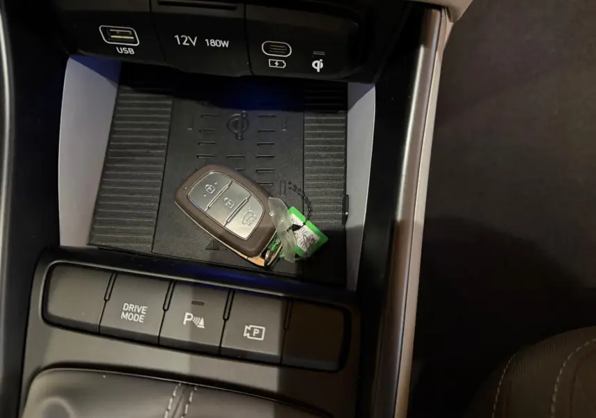 Gros plan sur la console centrale de la Hyundai Bayon rouge 2025, avec clé, boutons Drive Mode et aide au parking.