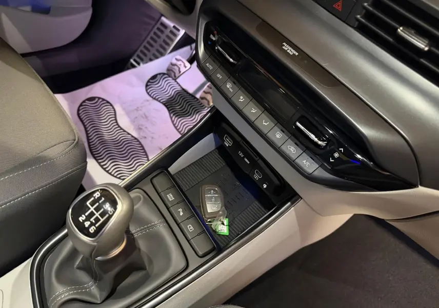Gros plan sur la console centrale intérieure grise et noire du Hyundai Bayon 2025 avec levier de vitesse manuel et clés posées.