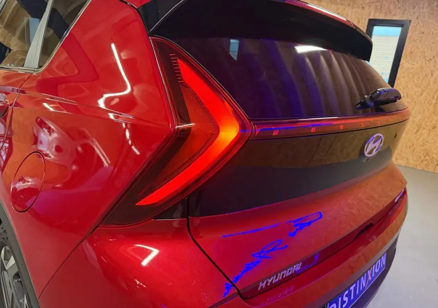 Feu arrière en forme de flèche rouge sur l'arrière droit d'une Hyundai Bayon rouge avec hayon noir laqué.