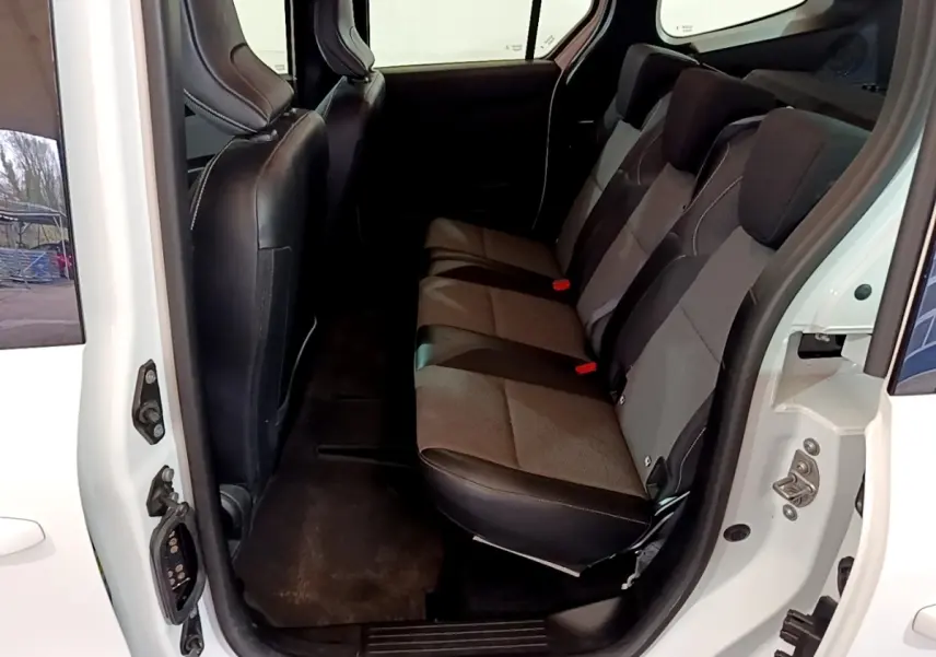 Vue intérieure côté droit sur la banquette arrière grise et noire du Renault Kangoo blanc, porte arrière ouverte.