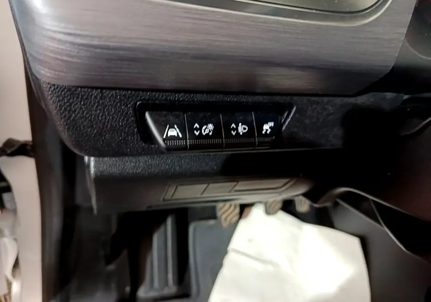 Vue intérieure du tableau de bord côté gauche du Renault Kangoo blanc, avec boutons de contrôle d’aides à la conduite.