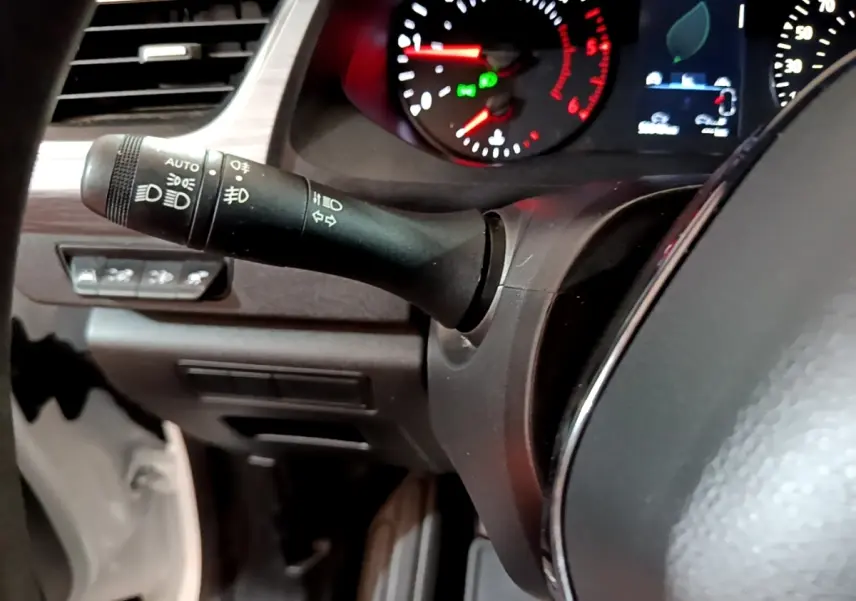 Gros plan sur la manette de commandes d’éclairage à gauche du volant dans le tableau de bord du Renault Kangoo blanc.