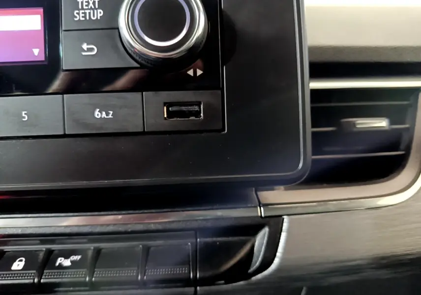 Gros plan sur la console centrale noire du Renault Kangoo blanc 2022, avec bouton de réglage et port USB visible.