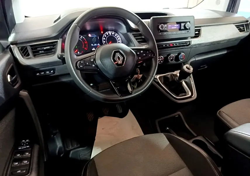 Vue intérieure avant du Renault Kangoo 2022 avec volant multifonctions, tableau de bord noir et levier de vitesse manuel.
