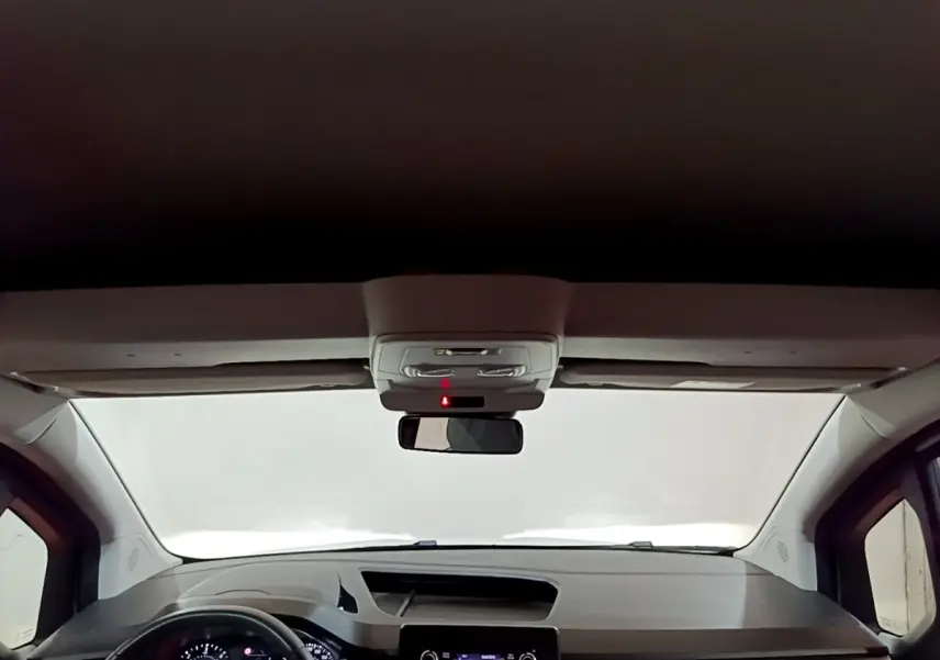 Vue intérieure avant du tableau de bord du Renault Kangoo blanc 2022 avec volant multifonctions et écran tactile central.