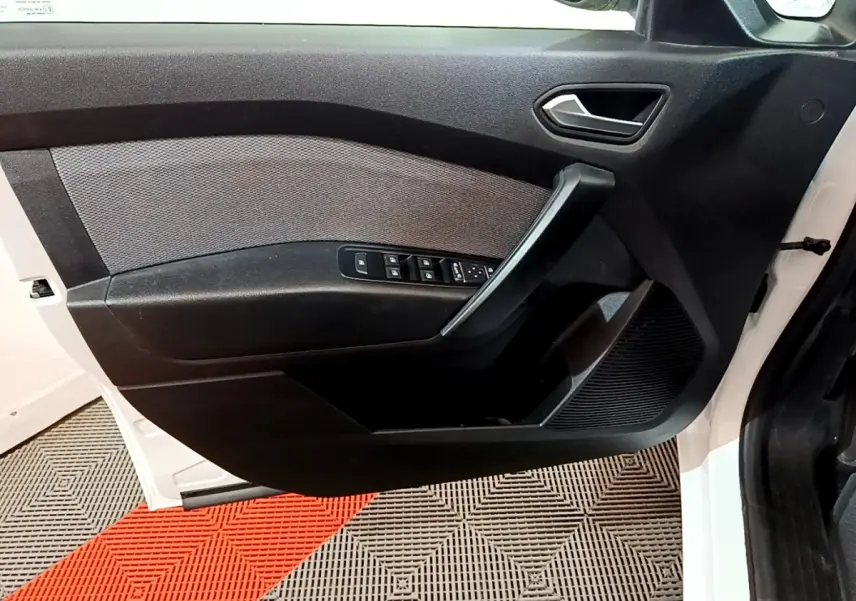 Vue rapprochée de la porte avant gauche blanche du Renault Kangoo Equilibre 2022 avec commandes de vitres et poignée noire.