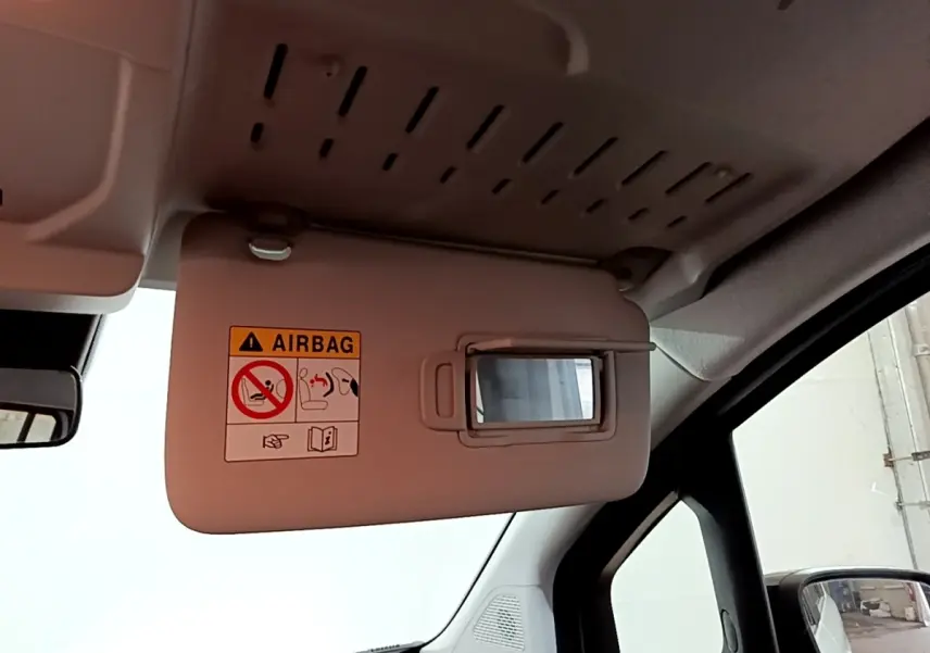 Détail de pare-soleil côté conducteur avec miroir intégré et avertissement airbag dans un Renault Kangoo blanc 2022.