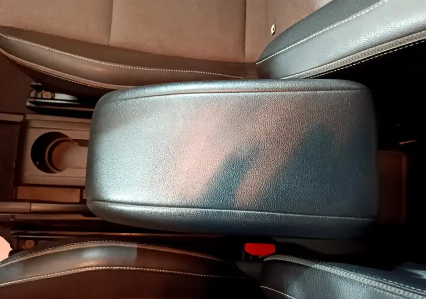 Gros plan sur l'accoudoir central noir entre les sièges avant du Renault Kangoo blanc, version Équilibre 2022.