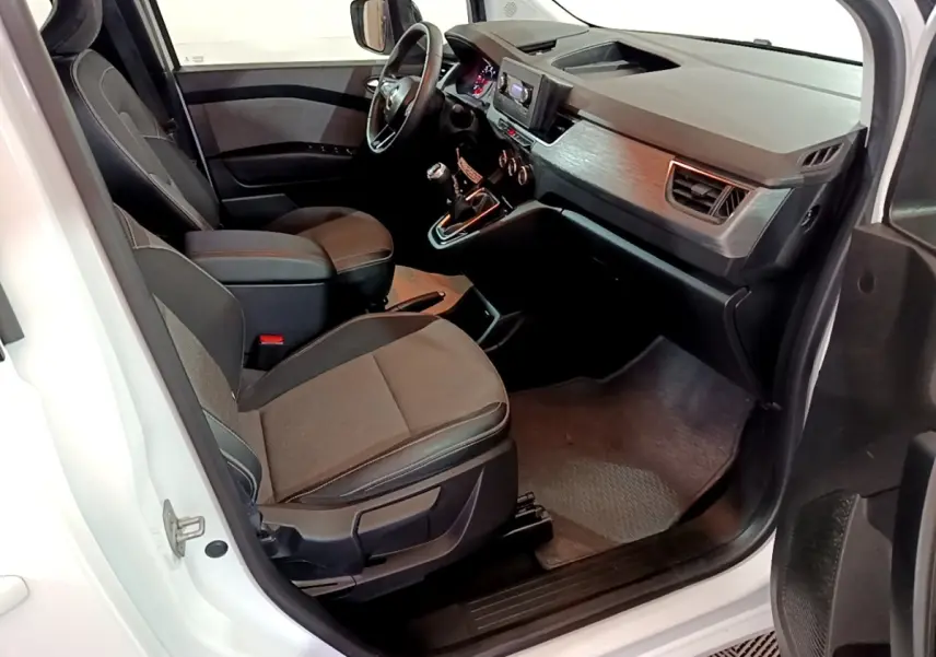 Vue intérieure côté conducteur du Renault Kangoo blanc 2022, montrant sièges tissu et tableau de bord avec écran tactile central.