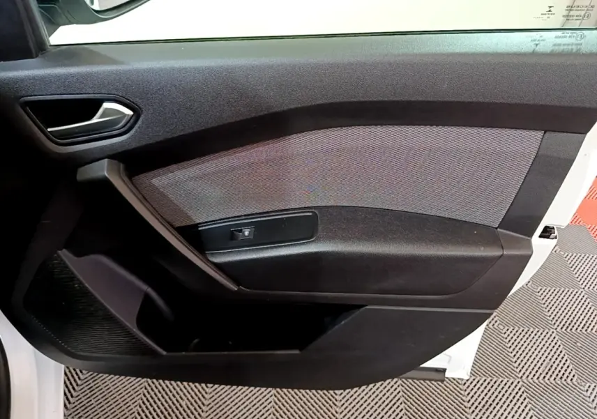 Vue intérieure côté gauche de la porte avant d’un Renault Kangoo blanc, avec panneau noir et commande de vitre électrique.