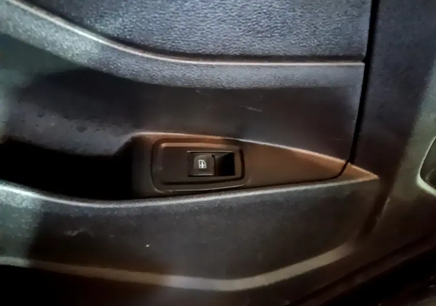 Gros plan sur le bouton de commande de la vitre électrique côté intérieur d'une Renault Kangoo Equilibre blanc 2022.