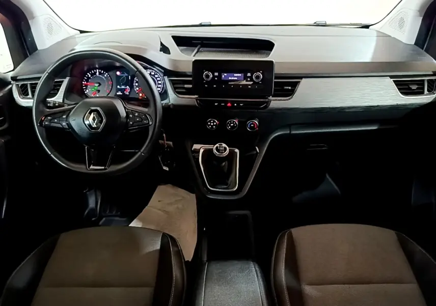 Vue intérieure frontale du tableau de bord du Renault Kangoo blanc 2022 avec volant multifonctions et boîte manuelle.