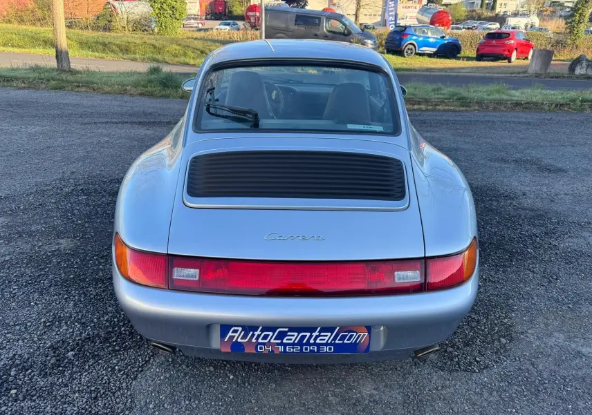 Vue arrière d'une Porsche 911 Carrera 993 gris polaire avec feu arrière continu et essuie-glace arrière visible.