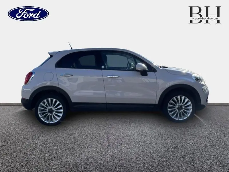 Vue de profil côté gauche d'une FIAT 500X argentée avec jantes alliage et vitres surteintées.